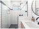 Bathroom features walk-in shower, round mirror, wood vanity, and white subway tile at 8115 Manasota Key Rd, Englewood, FL 34223