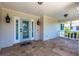 Inviting covered front porch with travertine tile flooring and a decorative front door with sidelights at 8115 Manasota Key Rd, Englewood, FL 34223