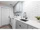 Laundry room with white appliances, gray cabinets, a sink, and a white subway tile backsplash at 8115 Manasota Key Rd, Englewood, FL 34223