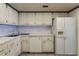 Bright kitchen featuring white cabinets, tile backsplash, modern appliances and tiled flooring at 851 Bayway Blvd # 403, Clearwater Beach, FL 33767