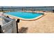 Community pool with a clear blue water, lounge chairs, and a secure fence at 851 Bayway Blvd # 403, Clearwater Beach, FL 33767