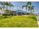 Expansive backyard with lush landscaping, a screened-in lanai, and a private boat dock for waterfront enjoyment at 925 Don Juan Ct, Punta Gorda, FL 33950