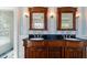 A dual vanity bathroom with dark countertops, wood cabinetry, and decorative sconce lighting at 110 Gilchrist St, Punta Gorda, FL 33950