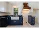 Well-appointed kitchen featuring white upper cabinets, black lower cabinets, and a farmhouse sink at 110 Gilchrist St, Punta Gorda, FL 33950