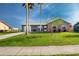 Inviting home featuring a lush green lawn, mature palm trees, and a neutral-toned exterior at 13449 Muriel Ave, Port Charlotte, FL 33981