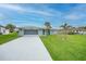Charming single-story home with a well-manicured lawn, palm trees, and a long driveway leading to a garage at 1756 Elinor Pl, Englewood, FL 34223