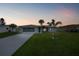 Charming single-story home with a well-manicured lawn, palm trees, and a long driveway at twilight at 1756 Elinor Pl, Englewood, FL 34223