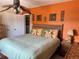 Inviting bedroom features a bamboo headboard, tropical ceiling fan and vibrant orange walls at 187 Beeney Se Rd, Port Charlotte, FL 33952