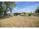 Exterior view of a yellow house with a screened-in lanai and a spacious backyard lawn at 20215 Macon Ln, Port Charlotte, FL 33952