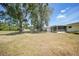 Spacious backyard featuring mature trees, a well-maintained lawn, and a screened-in patio for outdoor enjoyment at 20215 Macon Ln, Port Charlotte, FL 33952