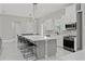 Open-concept kitchen featuring a large island with seating, white cabinets, stainless steel appliances, and modern lighting at 2186 Florala St, North Port, FL 34287