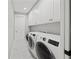 Well-lit laundry room with front load washer/dryer units and white cabinets for storage at 2186 Florala St, North Port, FL 34287