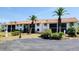 Condominium building featuring a red tile roof and white exterior with mature tropical landscaping and a paved parking lot at 2275 S Mccall Rd # 103, Englewood, FL 34224