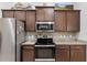 Well-lit kitchen features stainless steel appliances, brown cabinetry, and speckled granite countertops at 27147 Guapore Dr, Punta Gorda, FL 33983