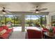 Screened patio with ceiling fans, red wicker furniture, grill, and view of the backyard, offering a relaxing outdoor space at 27147 Guapore Dr, Punta Gorda, FL 33983