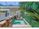 A well appointed hot tub adjoins an exterior brick wall with tropical accents and a stone waterfall feature at 3866 Turtle Dove Blvd, Punta Gorda, FL 33950