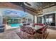 Outdoor dining area with brick columns, screened ceiling, chandelier, and pool with waterfall feature at 3866 Turtle Dove Blvd, Punta Gorda, FL 33950