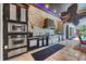 Outdoor kitchen featuring stainless steel appliances, stone backsplash and bar with view of covered pool at 3866 Turtle Dove Blvd, Punta Gorda, FL 33950