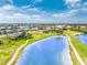 Panoramic aerial of a community with lush golf course, serene pond, and well-maintained homes with beautiful landscaping at 4015 La Costa Island Ct, Punta Gorda, FL 33950