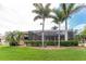Beautiful backyard showcasing a screened lanai surrounded by mature palm trees and well-manicured lawn at 4015 La Costa Island Ct, Punta Gorda, FL 33950