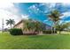 Rear exterior view of home with lush green lawn and landscaped border of tropical bushes and palm trees at 4015 La Costa Island Ct, Punta Gorda, FL 33950