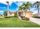 Beautiful home featuring mature palm trees, lush landscaping, and a well-maintained lawn and driveway at 4015 La Costa Island Ct, Punta Gorda, FL 33950