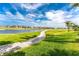 Scenic view of golf course with a lake, trees, and manicured green space under a beautiful blue sky with white clouds at 4015 La Costa Island Ct, Punta Gorda, FL 33950