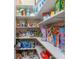 Organized walk-in pantry with an assortment of food and beverages on white shelves at 4015 La Costa Island Ct, Punta Gorda, FL 33950