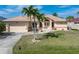 Charming single Gathering home featuring a well-manicured lawn, palm trees, and a two-car garage at 5720 Almar Dr, Punta Gorda, FL 33950