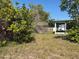 View of the overgrown backyard with a screen room and fence at 8782 La Boca Ave, North Port, FL 34287