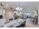 Open-concept dining room with chandelier, wood-look tile flooring, with a view into the living room and kitchen at 949 Springview Nw Ave, Port Charlotte, FL 33948