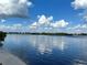 Scenic waterfront view showcasing calm, reflective water under a bright, cloudy sky at 949 Springview Nw Ave, Port Charlotte, FL 33948