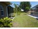 Green backyard featuring a screen-enclosed patio with lush plants and plenty of room for outdoor activities at 98 Valdiva St, Punta Gorda, FL 33983