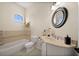 Traditional bathroom featuring a vanity, round mirror, shower-tub, and neutral color palette at 10580 Poughkeepsie Cir, Port Charlotte, FL 33981