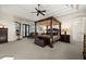 Spacious main bedroom with a four-poster bed, tray ceiling, and access to an outdoor sitting area at 10580 Poughkeepsie Cir, Port Charlotte, FL 33981