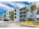Stylish waterfront condo building with blue exterior, multiple balconies, mature palm trees, and covered parking at 1750 Jamaica Way # 312, Punta Gorda, FL 33950