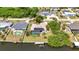Aerial view of a home with solar panels, screened-in pool, dock, and waterfront access in a lush, green neighborhood at 18753 Klingler Cir, Port Charlotte, FL 33948