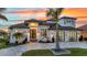 Stunning exterior of a modern home featuring a well-manicured lawn, palm trees, and decorative driveway pavers at sunset at 19 Sabal Dr, Punta Gorda, FL 33950