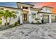 Modern home exterior with a geometric paver driveway, a two-car garage with glass doors, and tropical landscaping at 19 Sabal Dr, Punta Gorda, FL 33950