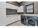 Contemporary laundry room featuring white cabinets, marble countertops, and modern washer and dryer at 19 Sabal Dr, Punta Gorda, FL 33950