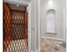 Home elevator with safety gate and elegant neutral colored travertine flooring on main level with a small hall bench and coat hooks at 2107 4Th Street W Ct, Palmetto, FL 34221