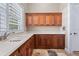 Laundry room with light countertops, wood cabinets, neutral paint, travertine floors, stainless steel sink and window with venetian blinds at 2107 4Th Street W Ct, Palmetto, FL 34221