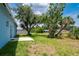 Large backyard with mature trees, a small patio, and lush green grass at 21480 Eldred Ave, Port Charlotte, FL 33952