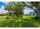 The home features a large backyard with mature trees and a lush lawn at 21480 Eldred Ave, Port Charlotte, FL 33952