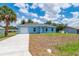 Charming single-story blue home featuring an attached garage and a well-manicured lawn at 21480 Eldred Ave, Port Charlotte, FL 33952