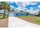 Charming single-story blue home featuring an attached garage and a well-manicured lawn at 21480 Eldred Ave, Port Charlotte, FL 33952