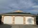 A three car garage featuring a matching green roof under a lightly clouded sky at 224 Boundary Blvd # 224L, Rotonda West, FL 33947