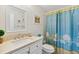 Well-lit bathroom with neutral countertop, white cabinets and a blue-themed shower curtain at 25100 Sandhill Blvd # R201, Punta Gorda, FL 33983