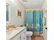 Well-lit bathroom with neutral countertop, white cabinets and a blue-themed shower curtain at 25100 Sandhill Blvd # R201, Punta Gorda, FL 33983