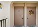 Close-up of tan unit entrance doors, one decorated with a colorful floral wreath at 25100 Sandhill Blvd # R201, Punta Gorda, FL 33983